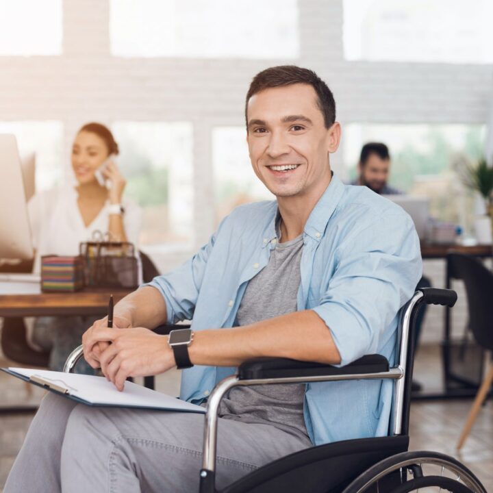 Disabled Man on Wheelchair with Tablet in Office.